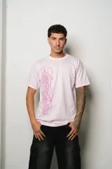 Remera de algodón color rosa pálido, corte regular fit, con un estampado vertical de estilo caligráfico en tono lila o rosado más oscuro en el centro del frente.