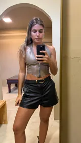 Top beige de cuero sintético con cuello halter y cierre frontal con cremallera.