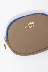 Monedero de forma ovalada marca Bimba y Lola, confeccionado en nylon color beige con detalles en verde oliva en el cierre y logo metálico dorado en el frente.