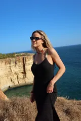 Vestido largo negro de punto con hilado brillante, tirantes finos con apliques decorativos de cuentas de colores, escote en V y espalda abierta con cordón ajustable. Presenta un pequeño tajo lateral en el bajo.