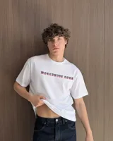 Remera blanca de manga corta, corte regular y cuello redondo, con gran estampado en la espalda de temática "Worldwide Tour" con una calavera y texto en rojo, azul y blanco.