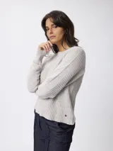 Sweater de punto con textura acanalada, de corte relajado y cuello a la base. Presenta mangas largas con abertura y un pequeño aplique metálico en el ruedo.