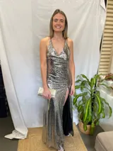 Vestido largo plateado de lentejuelas con escote en V, espalda baja y tajo en la pierna.