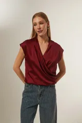 Blusa de satén color bordó, con diseño cruzado tipo sobre, cuello en V y mangas cortas integradas.