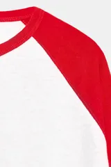 Camiseta de manga larga con diseño ranglan, cuerpo en color blanco y mangas en color rojo. Presenta cuello redondo y bajo recto.