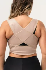 Top corrector de postura color piel, de alta tensión con bandas cruzadas en la espalda y broche delantero en bajo busto. Confeccionado con tela que contiene fibra LYCRA®.