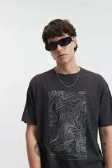 Remera de manga corta color lila, de corte regular y escote redondo, con estampa frontal de líneas topográficas y texto.