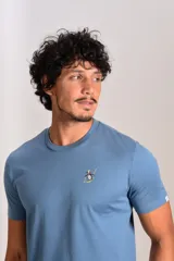 Remera de cuello redondo y manga corta en color azul, con un pequeño bordado de un pingüino esquiando en el pecho.