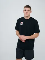 Remera de manga corta color beige, con cuello redondo y diseño holgado. Cuenta con un pequeño estampado rectangular en el pecho con motivo futbolero.