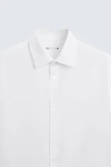 Camisa blanca de manga larga con cuello italiano y cierre frontal de botonadura. Corte regular fit.