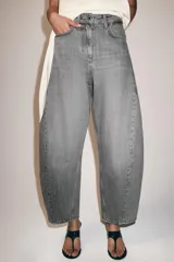 Jeans de tiro medio con diseño de pierna tipo balloon y largo al tobillo. Presenta cinco bolsillos, cierre frontal con cremallera y botón, y un acabado con efecto lavado.