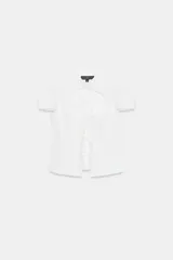 Camisa entallada de color blanco con cuello redondo, manga corta y abertura frontal. Presenta cierre con botones ocultos y detalle de lazadas en el frente.