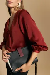 Blusa negra de satén con escote en V y detalle de volados frontales. Presenta mangas largas con puños abotonados y una silueta fluida.