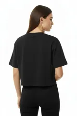 Remera blanca de algodón con cuello redondo y manga corta. Estampado frontal con la palabra "MERCI" en negro con efecto de puntos o tachas.