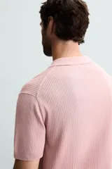 Polo de punto canalé color rosado, de corte regular fit, con cuello solapa y cierre frontal de botonadura. Manga corta y acabados en rib.