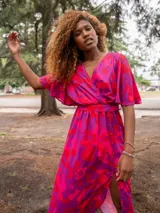 Vestido midi con estampado floral en tonos violeta y fucsia, con escote cruzado, mangas cortas tipo kimono, falda con abertura lateral y cinturón con hebilla forrada.