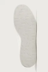 Zapatilla de cordones con parte superior fabricada en piel, de horma redonda y suela a tono.