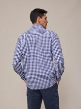 Camisa de manga larga para hombre, confeccionada en algodón con efecto peach (textura suave). Presenta un estampado de cuadros vichy en tonos azul marino y blanco, cuello con botones y un bolsillo de parche en el pecho izquierdo.