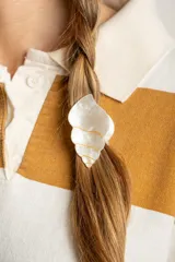 Broche con forma de caracola color blanco nacarado con detalles dorados.