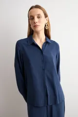 Camisa de corte clásico y calce holgado, con cuello camisero, cierre frontal de botones y mangas largas con puños abotonados.