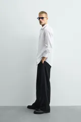 Camisa de corte slim fit confeccionada en tejido de algodón con textura. Presenta cuello italiano, manga larga con puños abotonados y cierre frontal mediante botonadura.