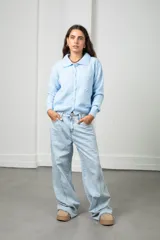 Saco tejido de punto color celeste, con cuello tipo polo, cierre frontal con botones a tono y diseño con flores bordadas en relieve. Posee mangas largas con puños acanalados y ruedo elástico.