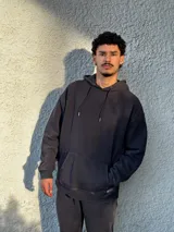 Buzo tipo canguro negro con capucha y cordones ajustables.