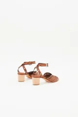 Sandalia de cuero vacuno color suela con diseño calado en la capellada y en la tira del tobillo. Presenta un taco bloque de madera y cierre con hebilla metálica.