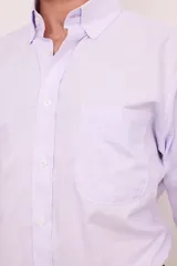 Camisa de corte clásico confeccionada en algodón, con diseño de rayas verticales finas en color rosa sobre fondo blanco. Presenta cuello abotonado, cierre frontal con botones, mangas largas con puños abotonados y un bolsillo en el pecho con el logo de la marca bordado.