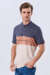 Remera polo de manga corta con diseño en bloques de color en tonos azul marino, blanco y verde militar, con bordado frontal y cierre de botones.