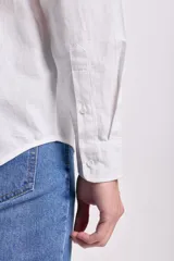 Camisa blanca de manga larga con cuello mao y cierre frontal con botones.