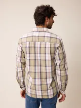 Camisa de manga larga con cuello abotonado y cierre frontal de botones. Presenta un diseño de cuadros en tonos beige, blanco y azul con líneas finas en rojo.