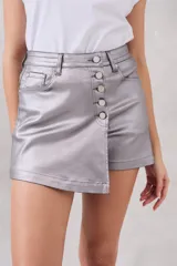 Skort plateada metalizada con cierre de botones frontal y corte asimétrico.