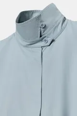 Camisa de algodón con cuello alto y mangas abullonadas por debajo del codo. Presenta cierre frontal con botones ocultos bajo solapa.
