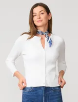 Cardigan blanco de tejido liviano con trama en relieve, cuello a la base y cierre frontal con botones a tono. Presenta mangas tres cuartos.