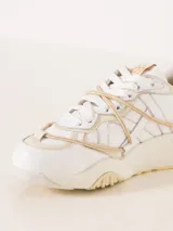 Zapatilla urbana color blanco con detalles en cuero color crema, con cordones y suela de goma.