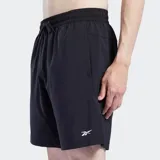 Short deportivo Reebok para hombre, color negro, con logo Reebok en blanco en la pierna izquierda. Presenta un ajuste regular, cintura elástica con cordón y bolsillos laterales.