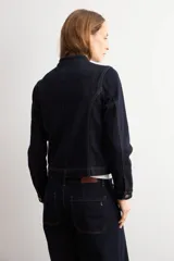 Chaqueta de jean azul oscuro, con cuello mao, cierre frontal de botones metálicos y dos bolsillos frontales de parche.