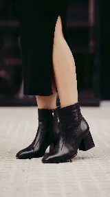 Bota corta de cuero con taco cuadrado y punta cuadrada. Presenta un diseño de líneas simples con cierre lateral y costura central en el empeine.