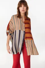 Vestido camisero corto con diseño de paneles combinados en distintos patrones de rayas verticales y horizontales, en tonos rojo, azul, beige y blanco. Posee cuello mao, cierre frontal con botones y mangas cortas caídas.