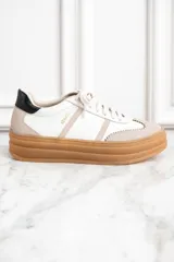Zapatillas bajas de cuero color blanco y beige, con suela gruesa marrón y cordones blancos.