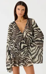 Vestido corto con estampado animal print tipo zebra, escote en V cruzado, mangas largas amplias y cintura fruncida elastizada con falda con volados.