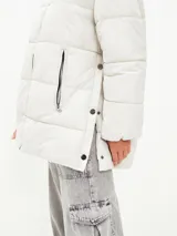 Campera puffer color blanco hueso, con cuello alto, cierre frontal con cremallera y bolsillos laterales con cierre.