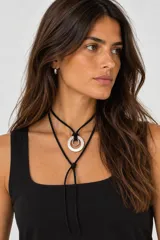 Collar de diseño artesanal con cordón de cuero negro regulable y dos piezas metálicas argolladas en níquel.