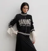 Campera tejida de algodón en color rojo, con cierre frontal completo, cuello alto y puños acanalados con detalles de rayas blancas. Presenta un diseño gráfico con texto blanco en el frente.