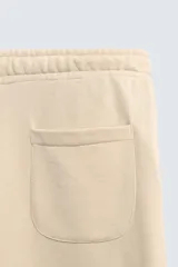 Pantalón jogger de corte relajado y pernera ancha, confeccionado en tejido de algodón con interior perchado. Cuenta con cintura elástica ajustable mediante cordón interior, bolsillos laterales y un bolsillo trasero de plastrón.