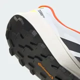 Championes de trail running Adidas Terrex Agravic 4, con diseño técnico en blanco, negro y detalles en naranja y amarillo neón. Presentan mediasuela Lightstrike para amortiguación ligera y suela de caucho Continental para tracción superior en terrenos variados.
