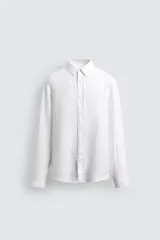 Camisa blanca de manga larga con cuello italiano y cierre frontal de botonadura. Presenta un calce regular fit y está confeccionada en tejido de lino.