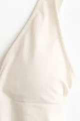 Soutien suave de punto seamless, color beige, con escote en V profundo, tirantes anchos y banda elástica en el bajo. Cuenta con copas con relleno extraíble.
