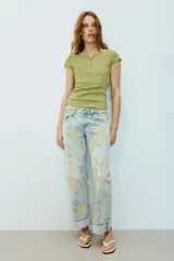Jeans de tiro bajo y corte holgado, color celeste con estampado floral en tonos amarillos y verdes. Presenta diseño de cinco bolsillos, trabillas para cinturón y dobladillo con vuelta en los bajos. Cierre frontal con cremallera y botón metálico.